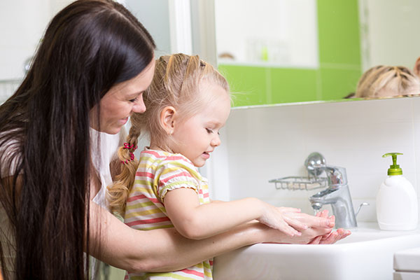 Smiling girl child and her mom washing hands with soap