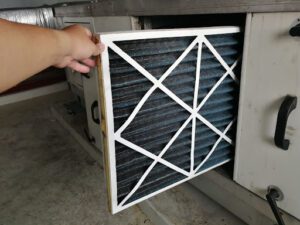A person replacing a dirty HVAC air filter.